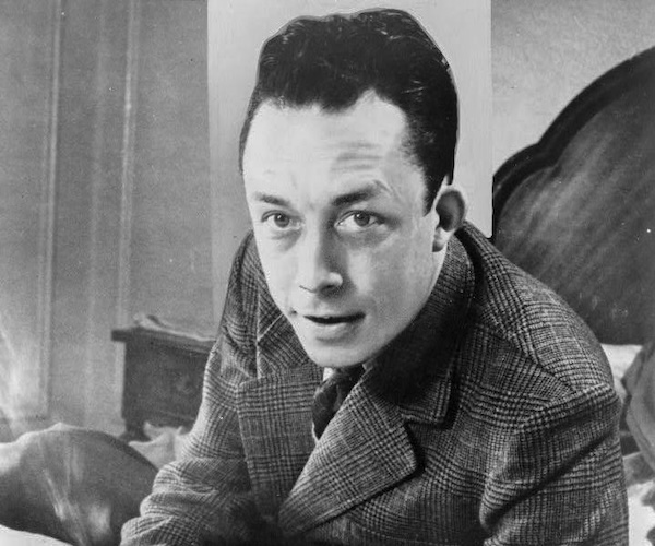 Albert_Camus,_gagnant_de_prix_Nobel,_portrait_en_buste,_posé_au_bureau,_faisant_face_à_gauche,_cigarette_de_tabagisme