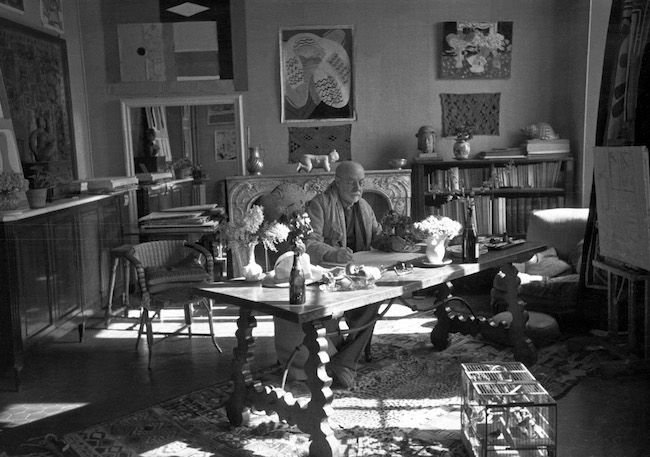 Photograph by Henri Cartier-Bresson (1908-2004) of Matisse with his collection of Kuba cloths and a Samoan tapa on the wall behind him, Villa La Rêve, Vence, 1944*© Henri Cartier-Bresson/Magnum. Photo: Courtesy Museum of Fine Arts, Boston